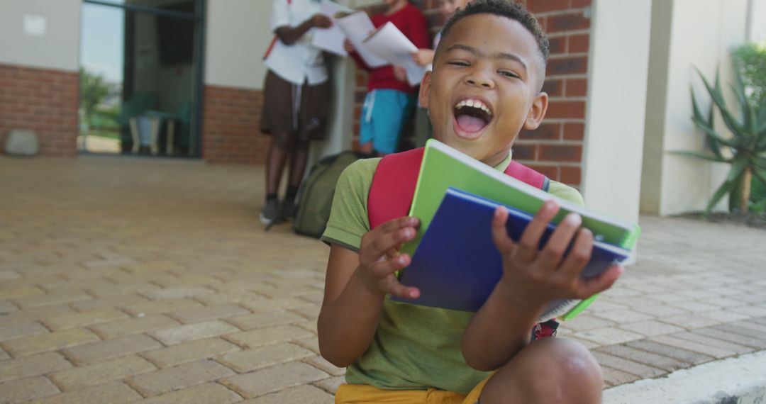Joyful African American Boy with Books Outside School