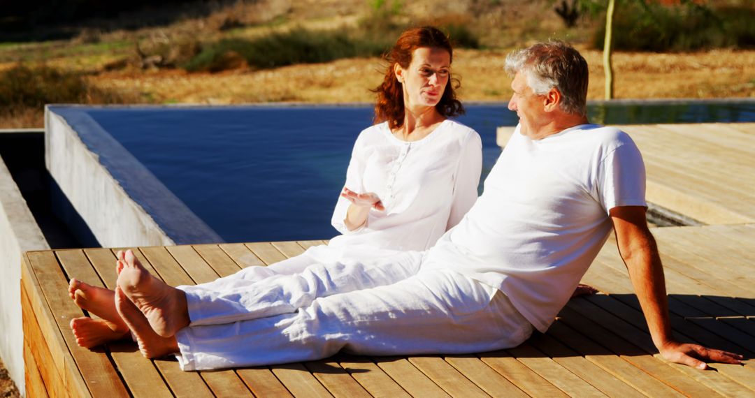 Senior Couple Relaxing by Pool During Sunny Day - Free Images, Stock Photos and Pictures on Pikwizard.com