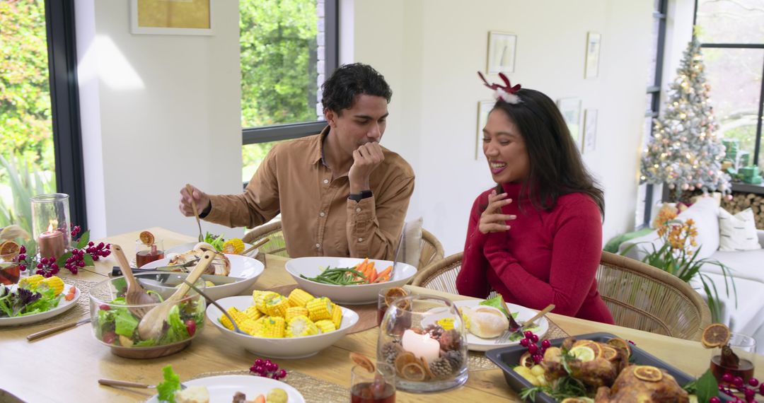 Couple Sharing Festive Holiday Meal at Bright Modern Dining Table with Christmas Tree