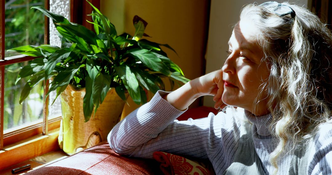 Mature Woman Relaxing Near Window with Sunlight - Free Images, Stock Photos and Pictures on Pikwizard.com