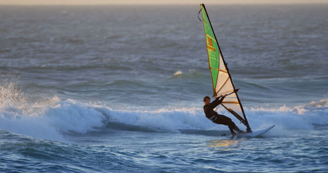 Experienced windsurfer riding waves at sunset - Free Images, Stock Photos and Pictures on Pikwizard.com