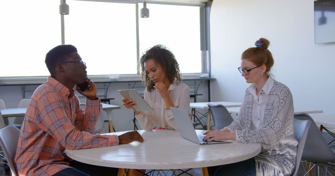 Diverse Professionals Using Multimedia Devices in Modern Office