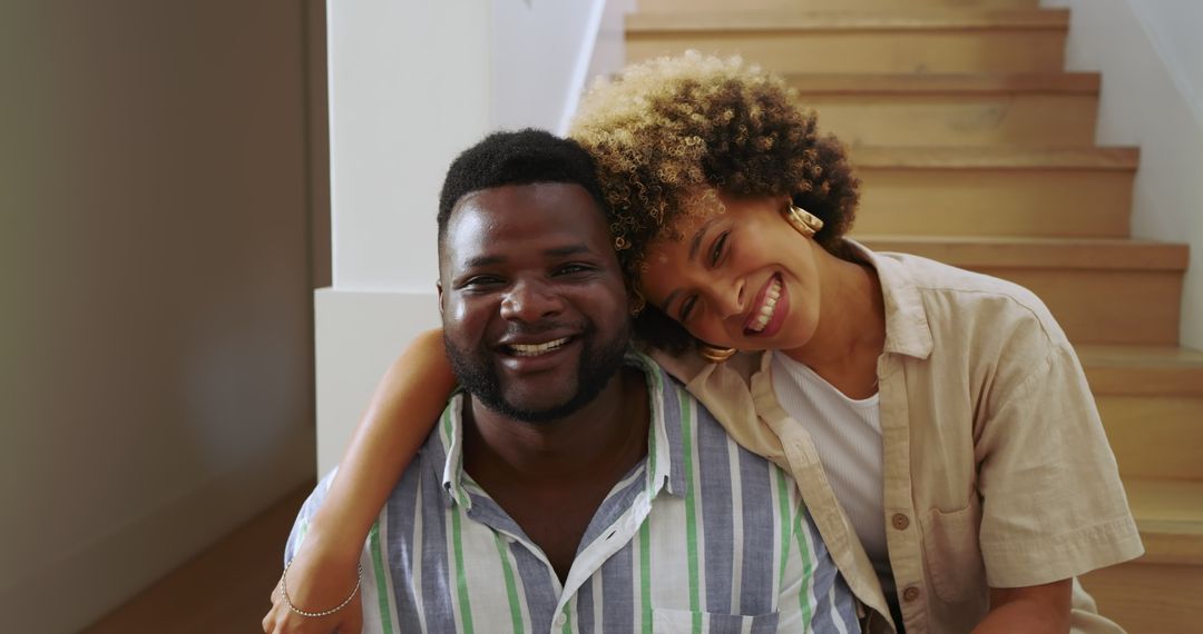 Diverse Couple Embracing on Home Stairs with Warm Smiles