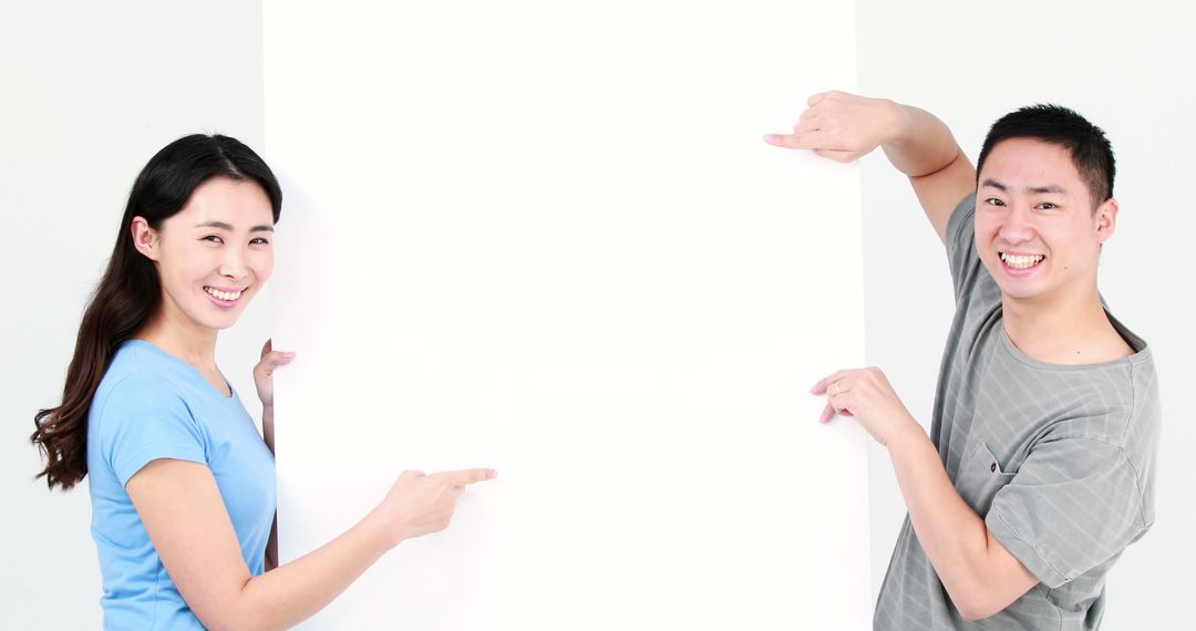 Cheerful Asian Friends Pointing at Blank Copy Space