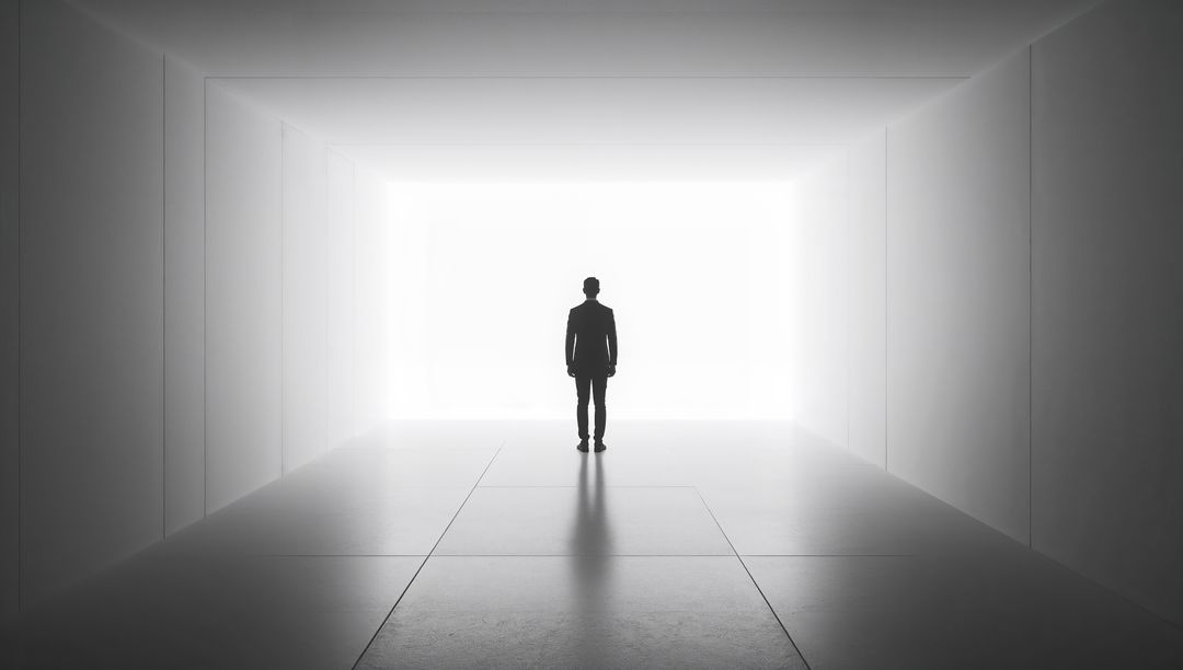 Standing businessman facing bright exit in minimalist corridor silhouette and symmetry