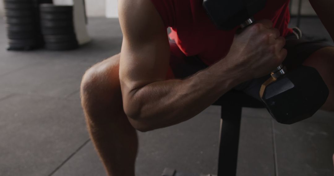 Focused Male Athlete Doing Dumbbell Curls in Gym
