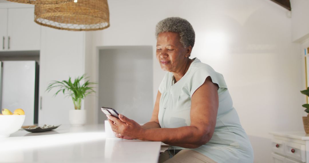 Senior African American Woman Using Smartphone in Modern Kitchen - Free Images, Stock Photos and Pictures on Pikwizard.com