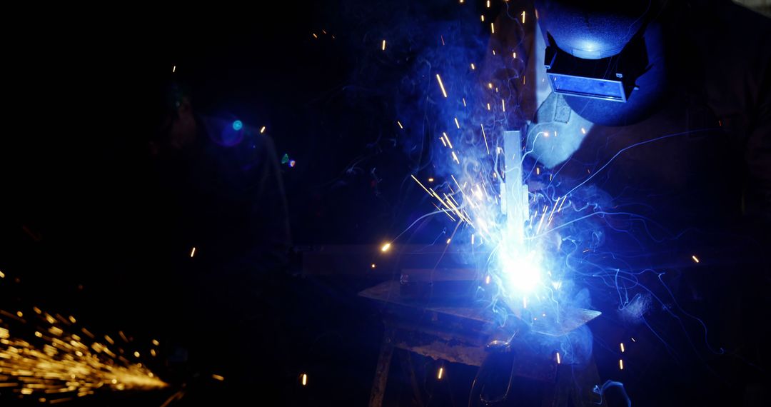 Welder Working with Bright Sparks in Dark Workshop - Free Images, Stock Photos and Pictures on Pikwizard.com