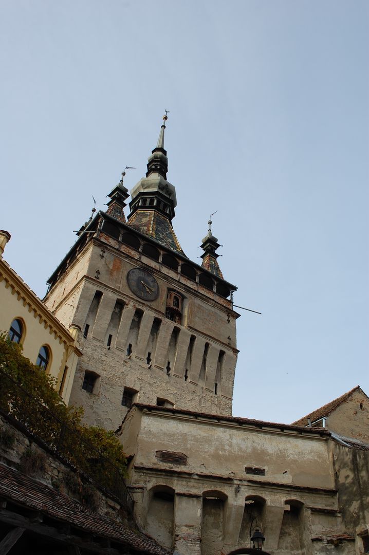 Towering medieval clock tower with colorful tiled spire overlooking old Transylvanian town