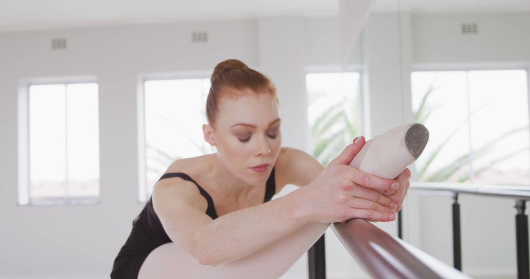 Determined Ballerina Practicing at Barre in Dance Studio