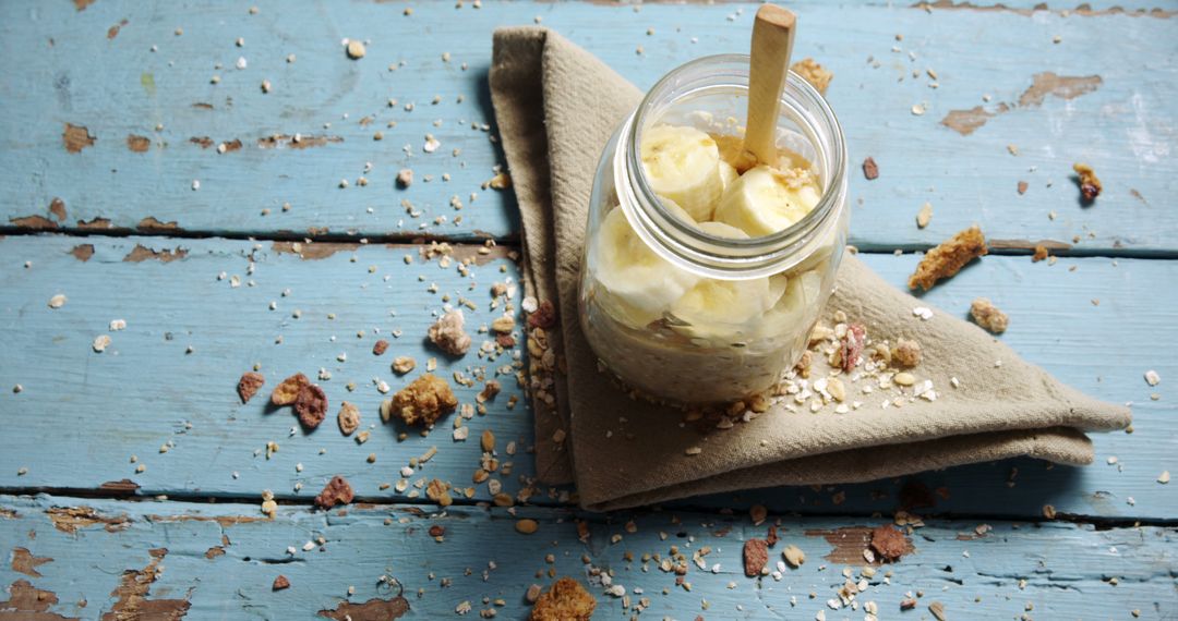 Breakfast Jar with Yogurt, Banana, and Oats on Rustic Wood