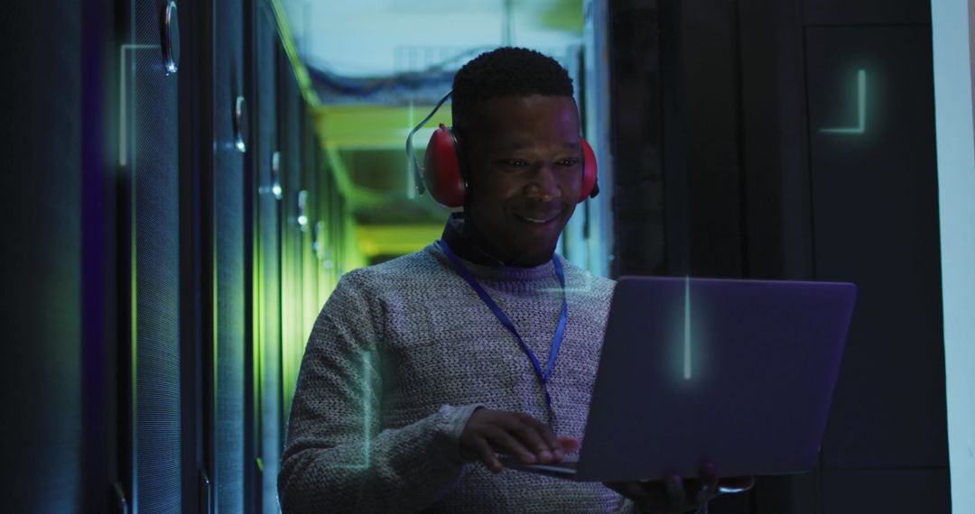 Smiling IT Technician Managing Servers with Laptop