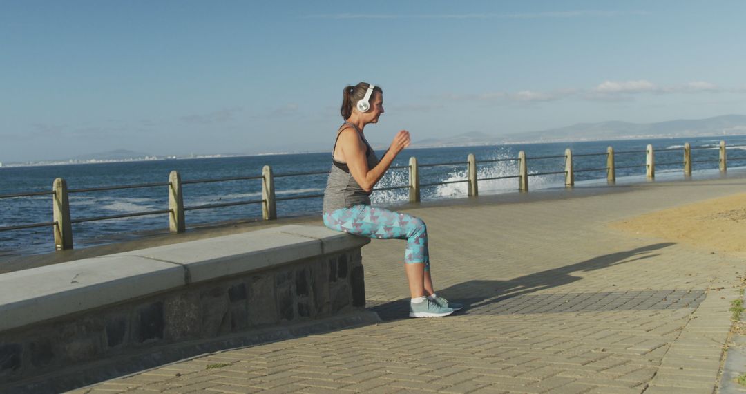 Woman Exercising with Headphones by Seaside Path - Free Images, Stock Photos and Pictures on Pikwizard.com