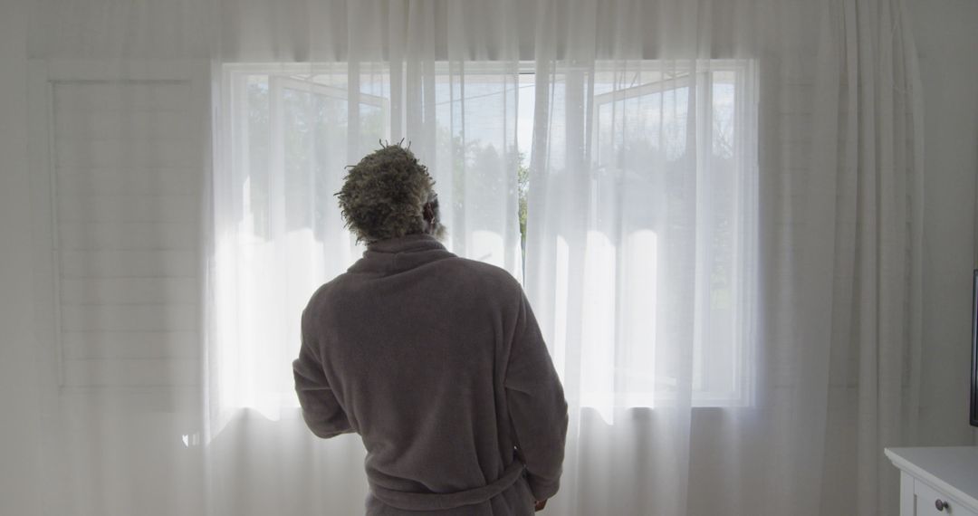 Man in Bathrobe Looking Out Window Through Sheer Curtains - Free Images, Stock Photos and Pictures on Pikwizard.com