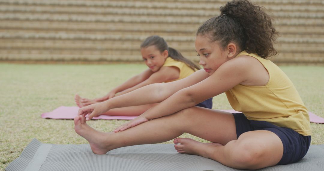 Young girls stretching during outdoor yoga session on mats - Free Images, Stock Photos and Pictures on Pikwizard.com