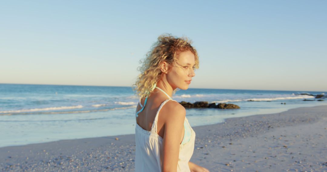 Woman with Blonde Curly Hair Walking on Sunny Beach - Free Images, Stock Photos and Pictures on Pikwizard.com