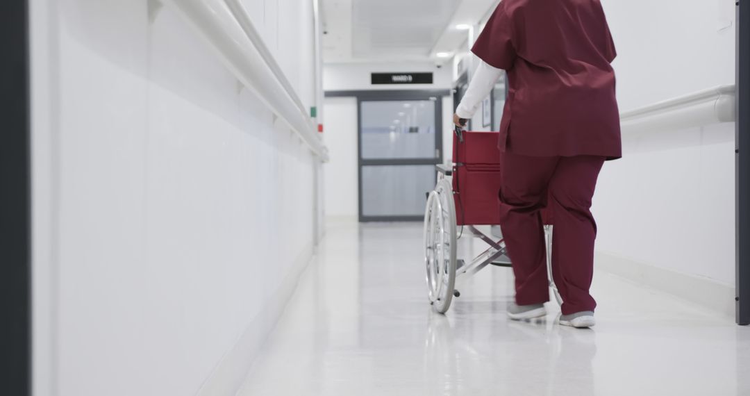 Healthcare Worker Pushing Wheelchair Down Hospital Corridor - Free Images, Stock Photos and Pictures on Pikwizard.com