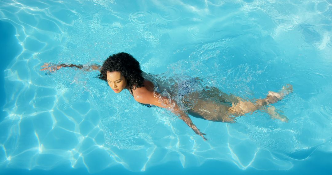 Woman with Curly Hair Swimming Breaststroke in Blue Pool - Free Images, Stock Photos and Pictures on Pikwizard.com