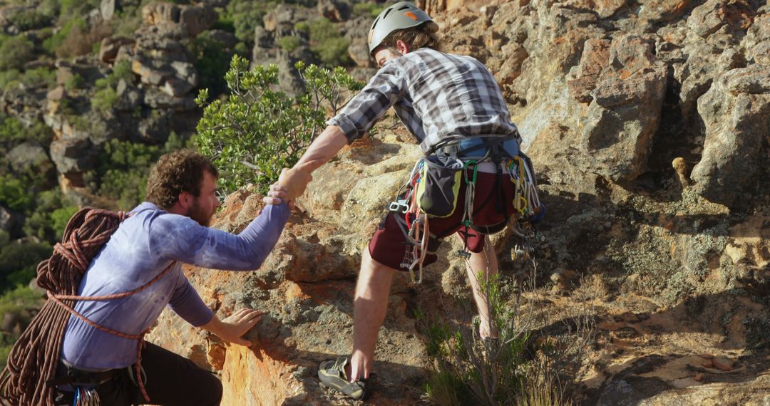 Rock climber helping friend at mountain summit achieving goal - Free Images, Stock Photos and Pictures on Pikwizard.com