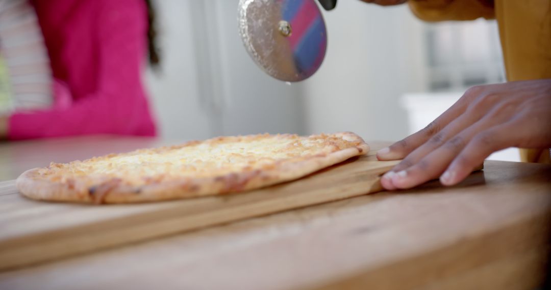 Person Cutting Cheese Pizza with Pizza Cutter in Kitchen - Free Images, Stock Photos and Pictures on Pikwizard.com