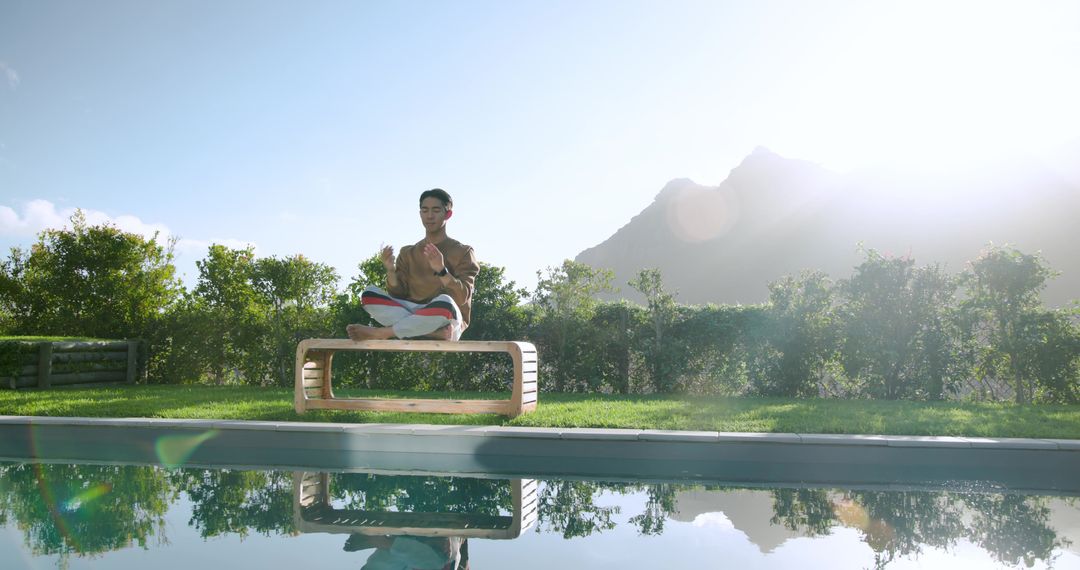 Man Meditating by Pool with Mountain Reflection in Background