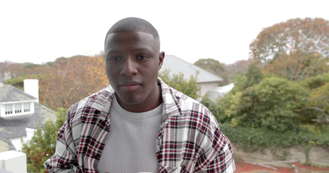 Young Man Standing Outdoors in Plaid Shirt - Free Images, Stock Photos and Pictures on Pikwizard.com