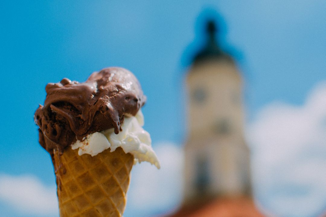 Chocolate Ice Cream Cone in Front of Tower on Sunny Day - Free Images, Stock Photos and Pictures on Pikwizard.com