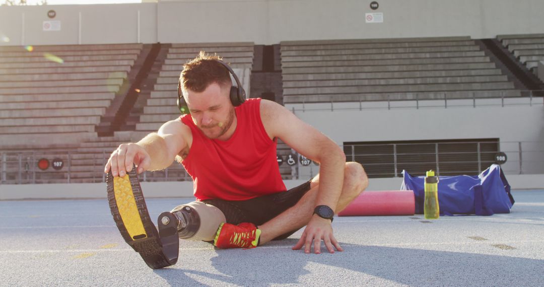 Paralympic Athlete Stretching at Track with Prosthetic Leg and Headphones - Free Images, Stock Photos and Pictures on Pikwizard.com