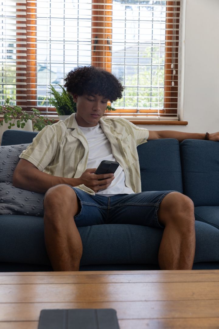 Casual Man Relaxing with Smartphone in Modern Living Room