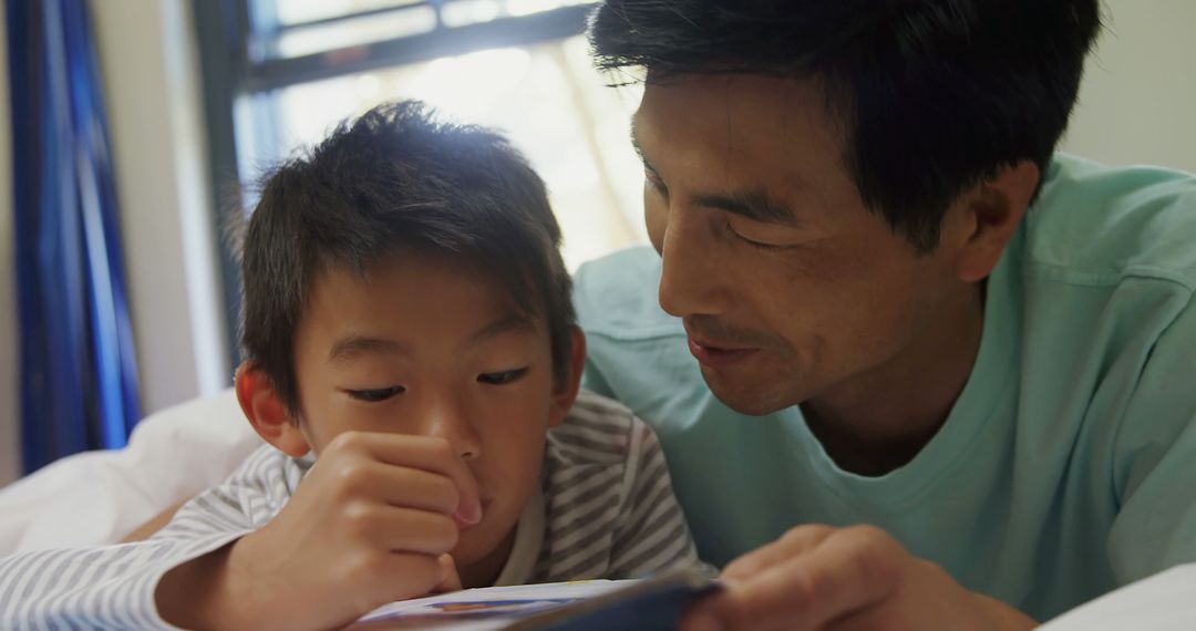 Father Reading Book with Young Son in Bed - Free Images, Stock Photos and Pictures on Pikwizard.com