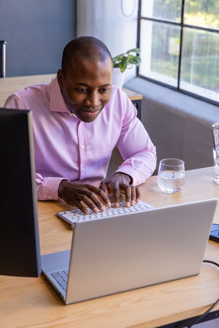 Focused Professional Typing at Modern Workspace with Large Window