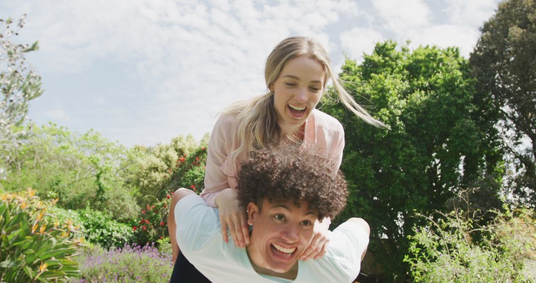 Joyful Couple Enjoying Playful Moment in Lush Garden on Sunny Day