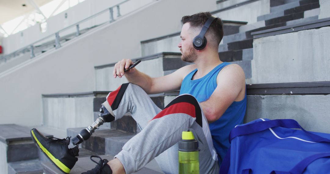 Male Athlete with Prosthetic Leg Relaxing on Stadium Steps and Listening to Music - Free Images, Stock Photos and Pictures on Pikwizard.com