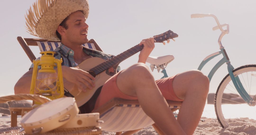 Man Relaxing on Beach Playing Ukulele with Bicycle in Background - Free Images, Stock Photos and Pictures on Pikwizard.com