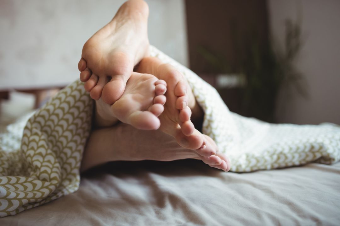 Couple showing their feet while lying on a bed - Free Images, Stock Photos and Pictures on Pikwizard.com
