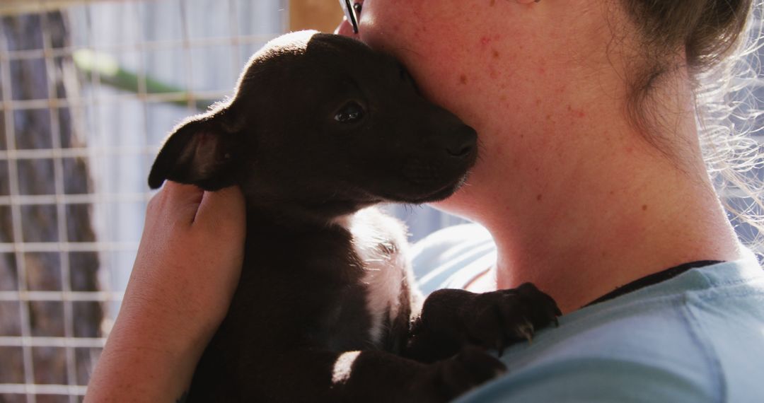 Woman Holding and Cuddling Black Puppy Close to Face - Free Images, Stock Photos and Pictures on Pikwizard.com