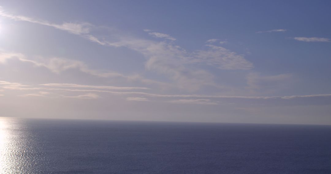Tranquil Ocean Horizon with Soft Sunlight and Gentle Clouds