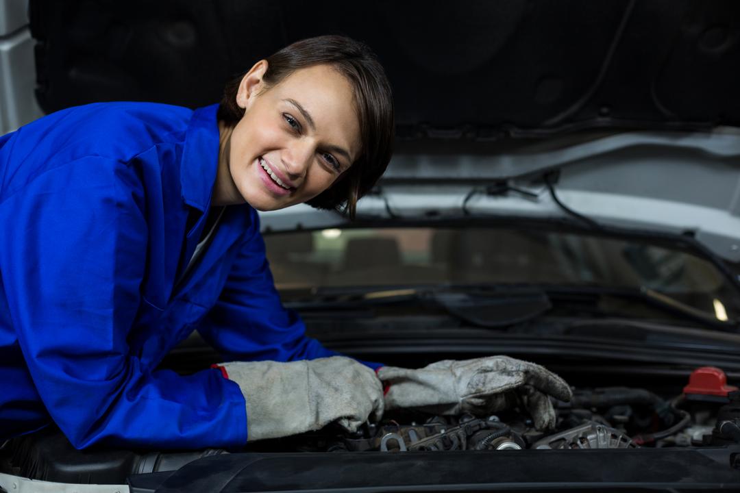 Female mechanic smiling while examining a car - Free Images, Stock Photos and Pictures on Pikwizard.com