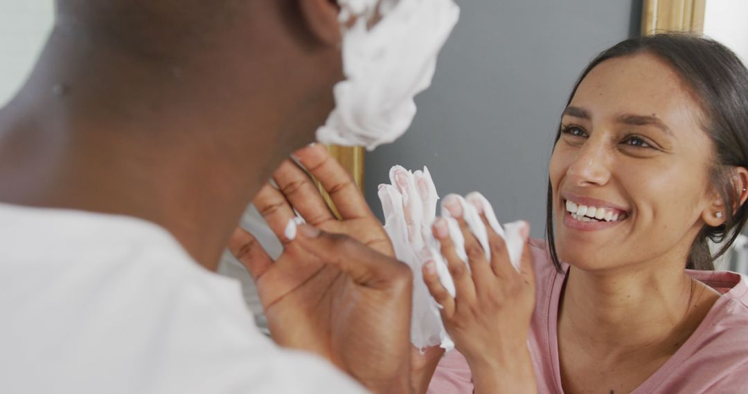 Image of happy diverse couple having fun putting shaving cream on man's face, laughing in bathroom - Free Images, Stock Photos and Pictures on Pikwizard.com