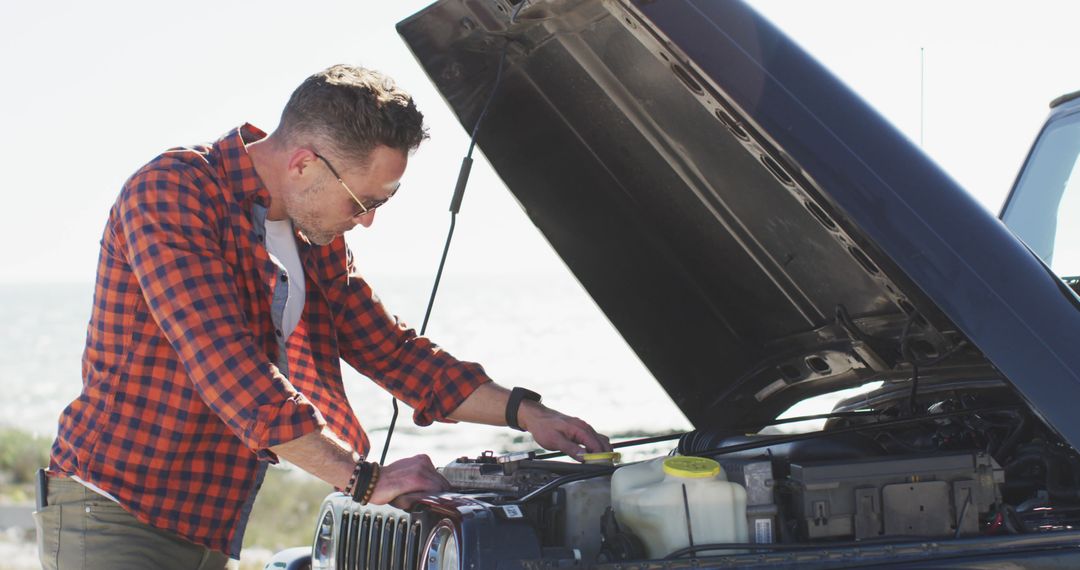 Man fixing car on roadside with sunlit ocean backdrop - Free Images, Stock Photos and Pictures on Pikwizard.com