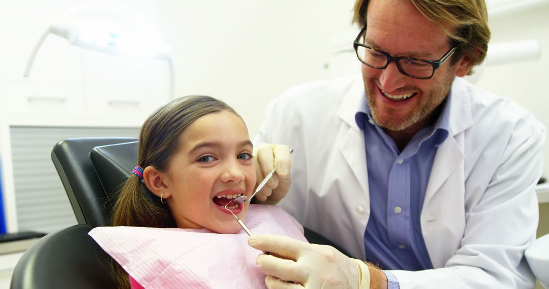 Smiling Dentist Treating Young Girl at Dental Clinic - Free Images, Stock Photos and Pictures on Pikwizard.com