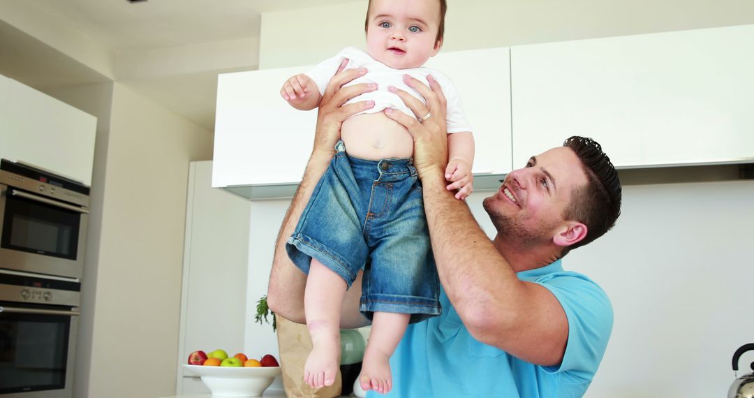 Dad Holding Baby in Relaxed Home Kitchen Setting - Free Images, Stock Photos and Pictures on Pikwizard.com