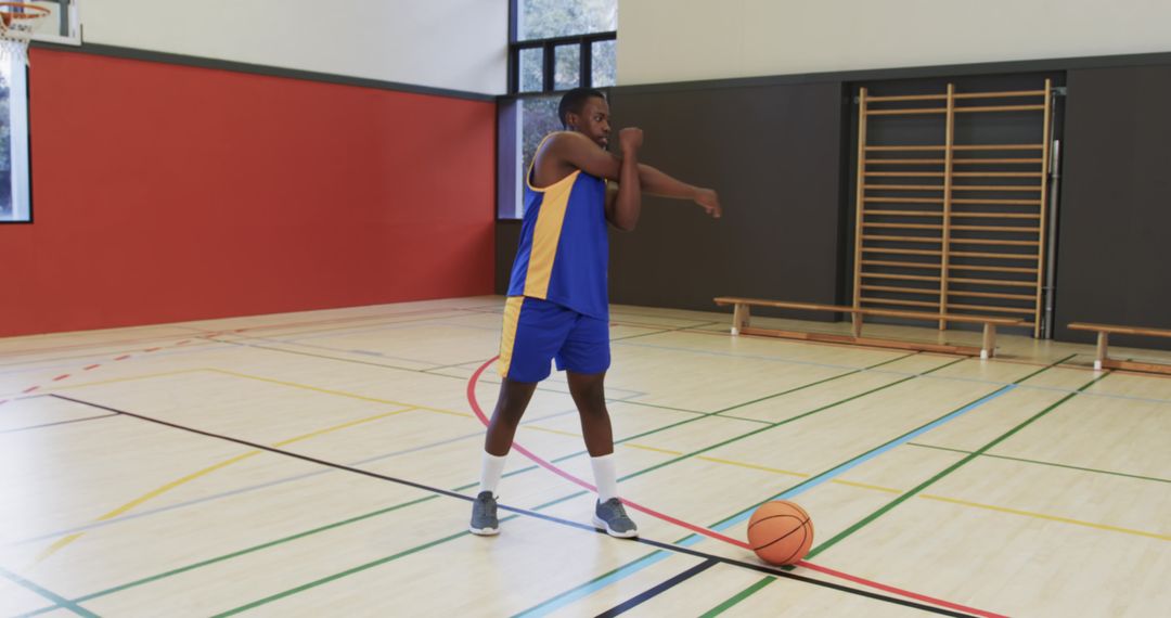 Young Basketball Player Stretching in Gym Before a Game