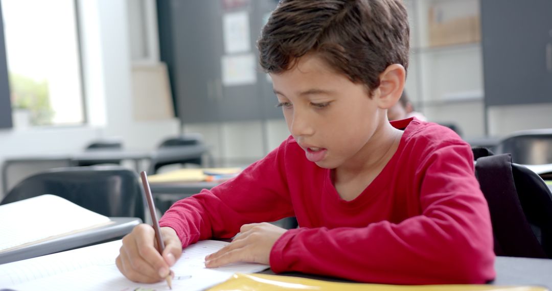 Focused Young Boy Writing in Classroom During School Day