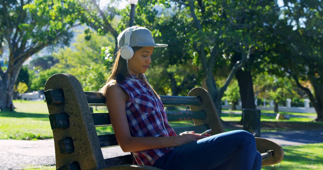 Young Woman Relaxing in Park Wearing Headphones and Plaid Shirt - Free Images, Stock Photos and Pictures on Pikwizard.com