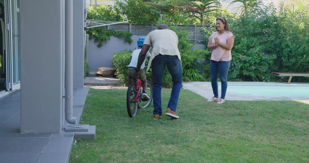 Father Teaching Son to Ride Bicycle in Backyard