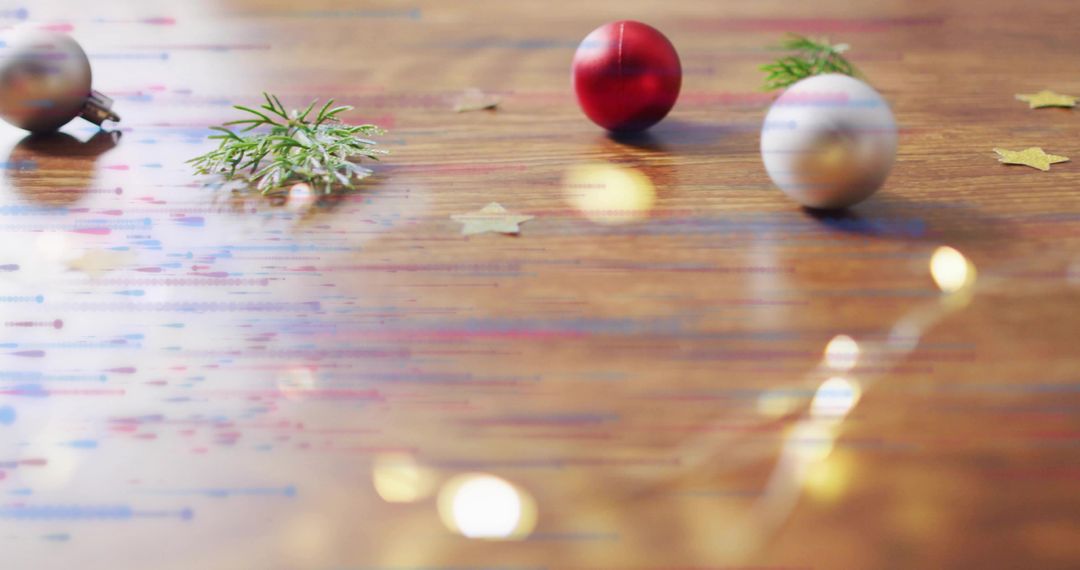 Festive red and silver baubles on wooden table with warm fairy light bokeh and evergreen