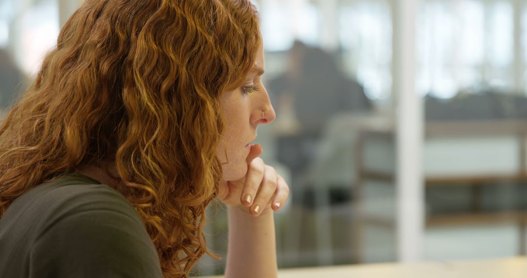 Focused Woman with Curly Red Hair Deep in Thought at Office Desk - Free Images, Stock Photos and Pictures on Pikwizard.com