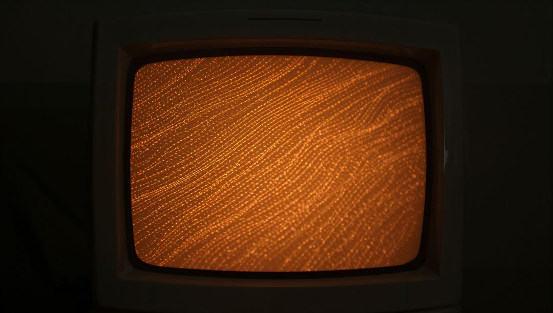 Glowing Orange Dotted Pattern Displaying on Vintage CRT Monitor with Curved Glass Bezel