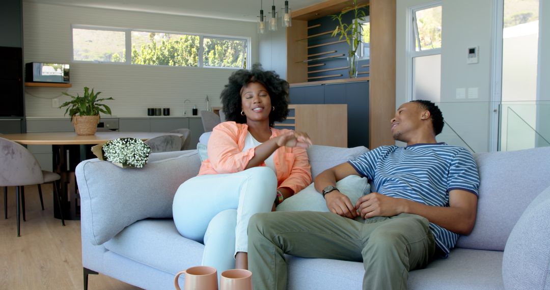 Happy Couple Relaxing on Sofa with Coffee at Home